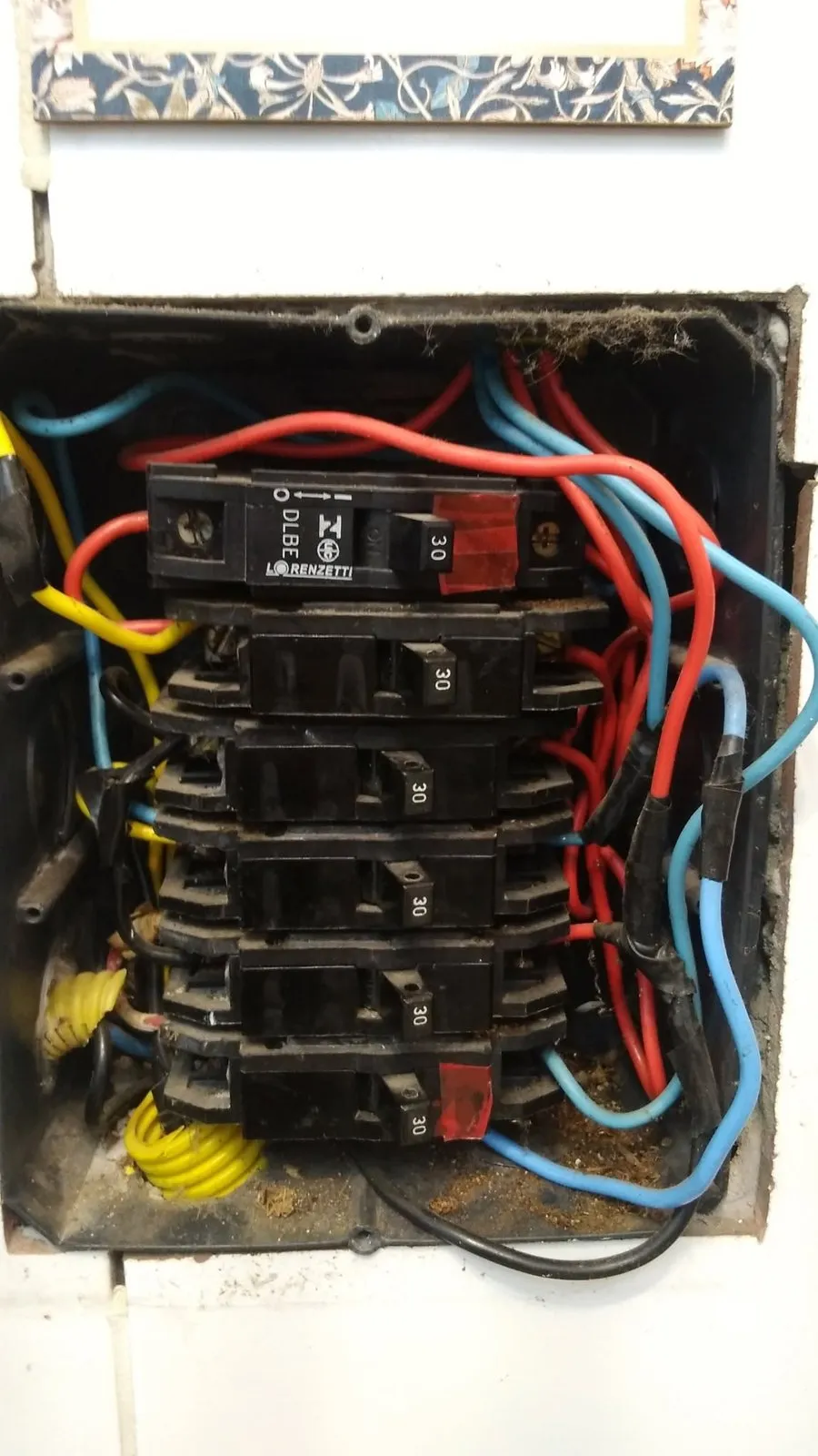 Quadro antigo com disjuntores velhos e fiação emendada com fita
